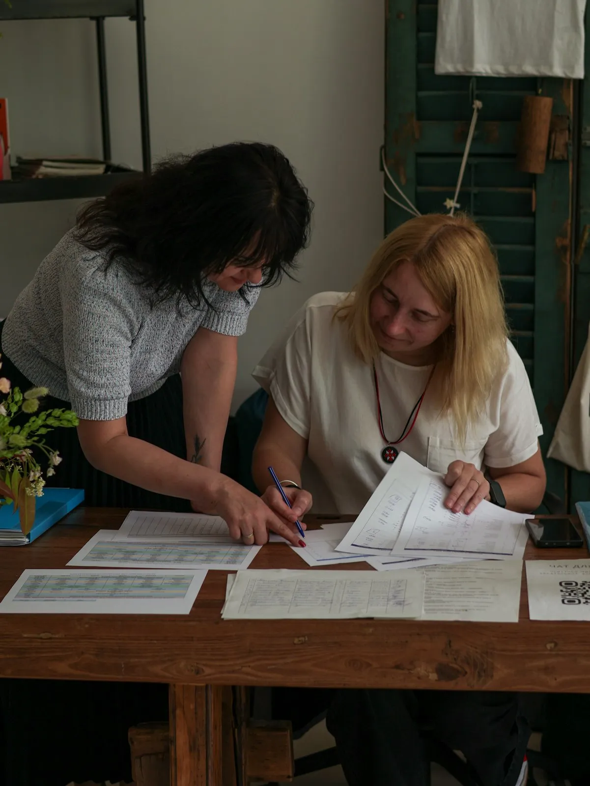 Two women going through papers at a table, one signing.