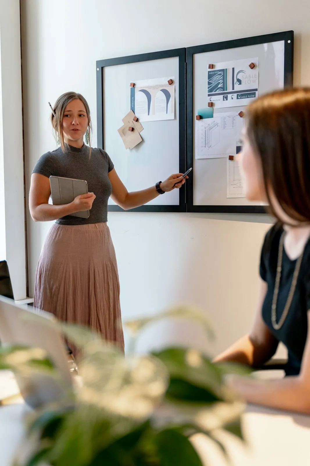 A consultant talking a colleague through notes on a pinboard.