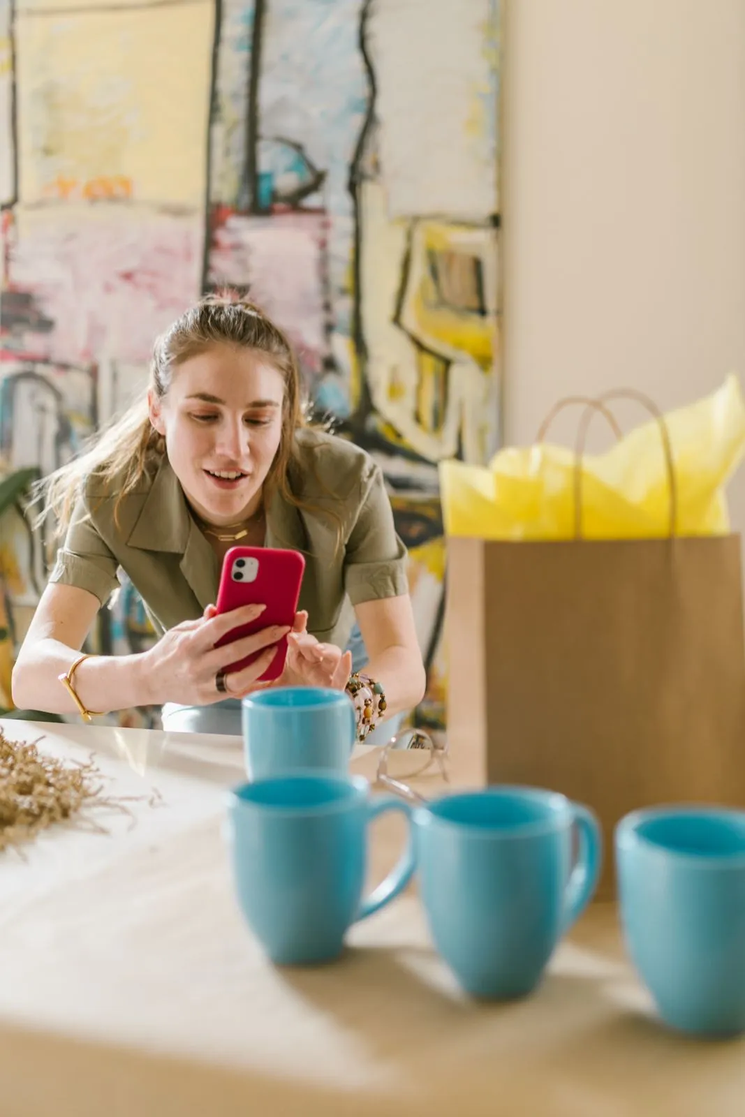 A shop owner photographing her mugs with her phone for her online shop.