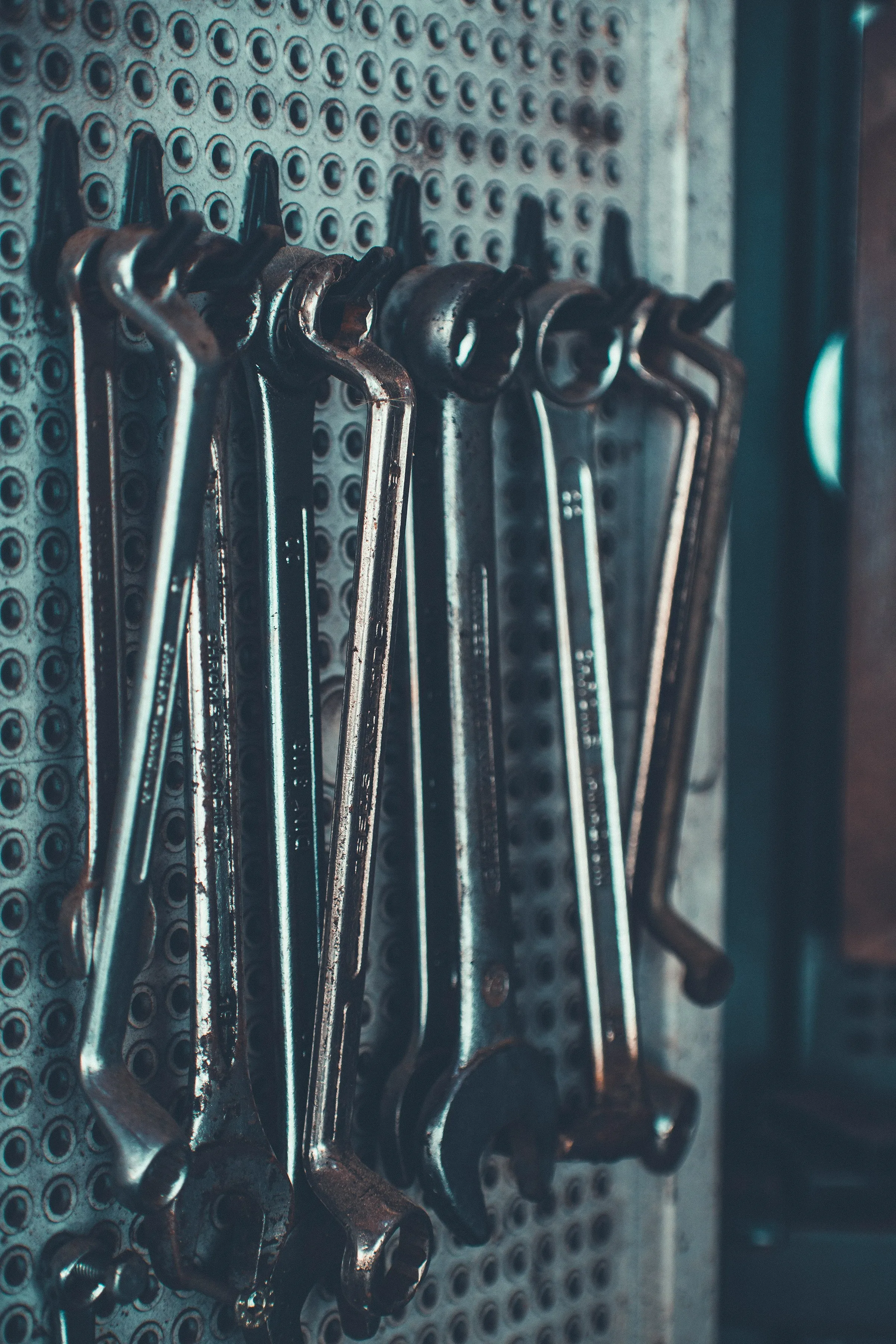 Spanners hanging in a row on a workshop pegboard.